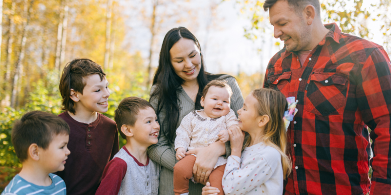 Family of 4 with mom and dad outdoors for a photoshoot