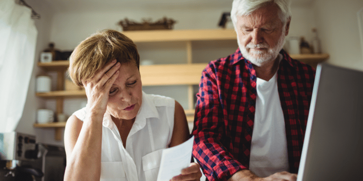 Mature couple looking at bills stressed about money